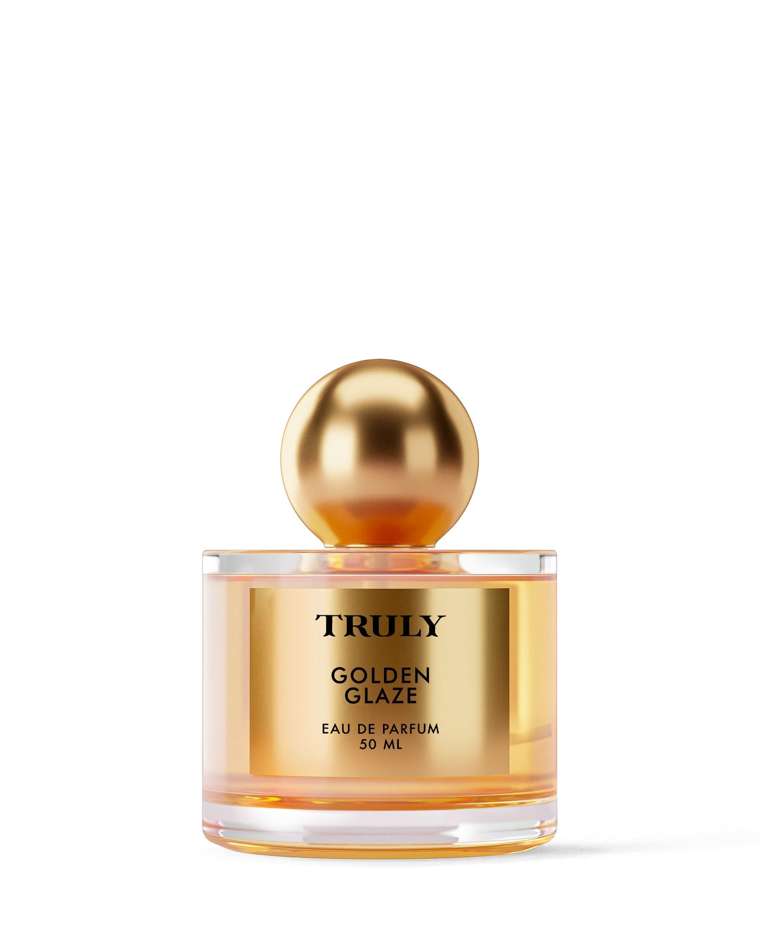 A 50ml glass bottle of Truly Beauty Golden Glaze Eau De Parfum, featuring a gold label and shiny gold spherical cap on a plain white background. Warm notes of smoldering chestnut and pink pepper enhance this elegant fragrance.