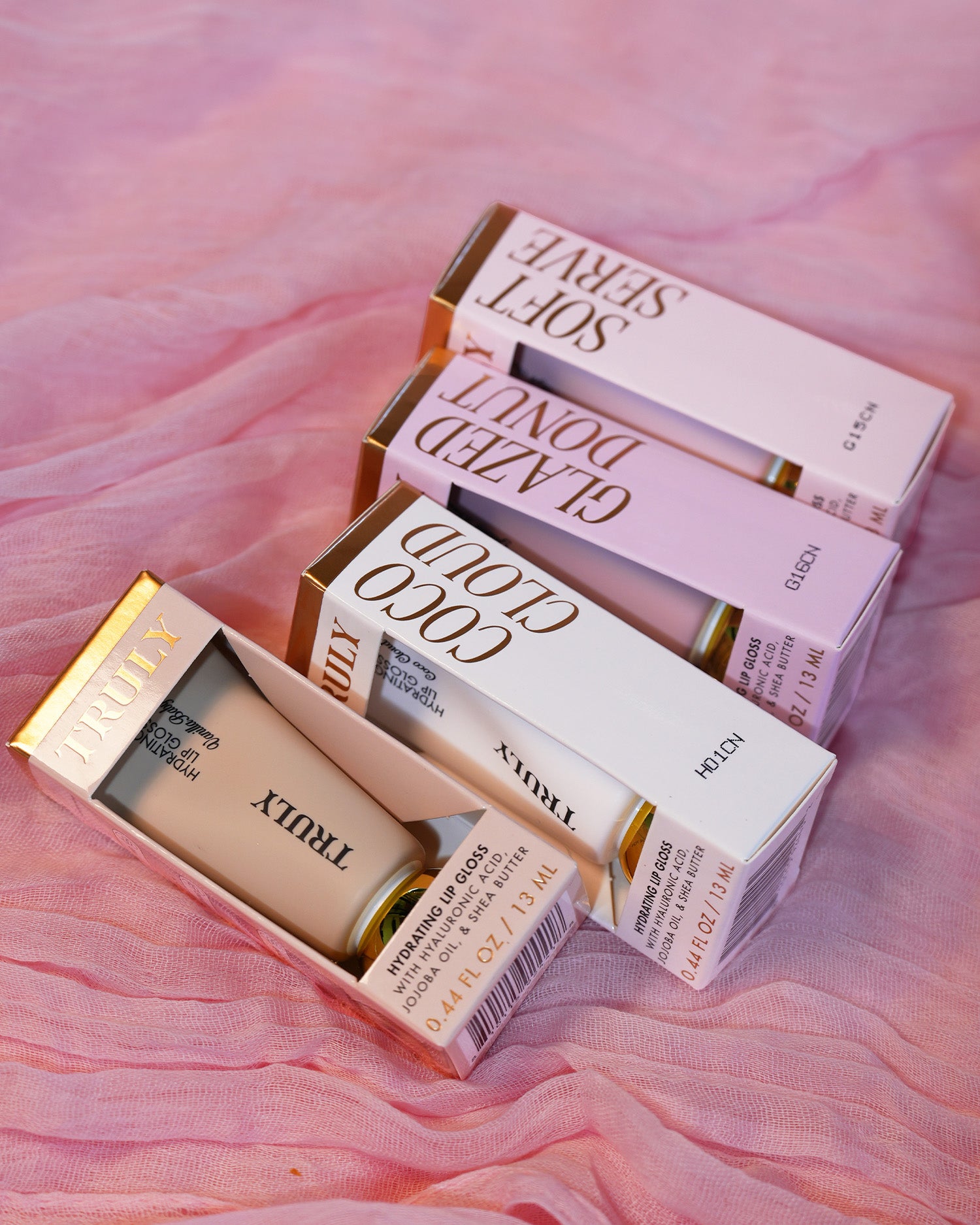 Makeup products including lipsticks and a foundation on a pink fabric background