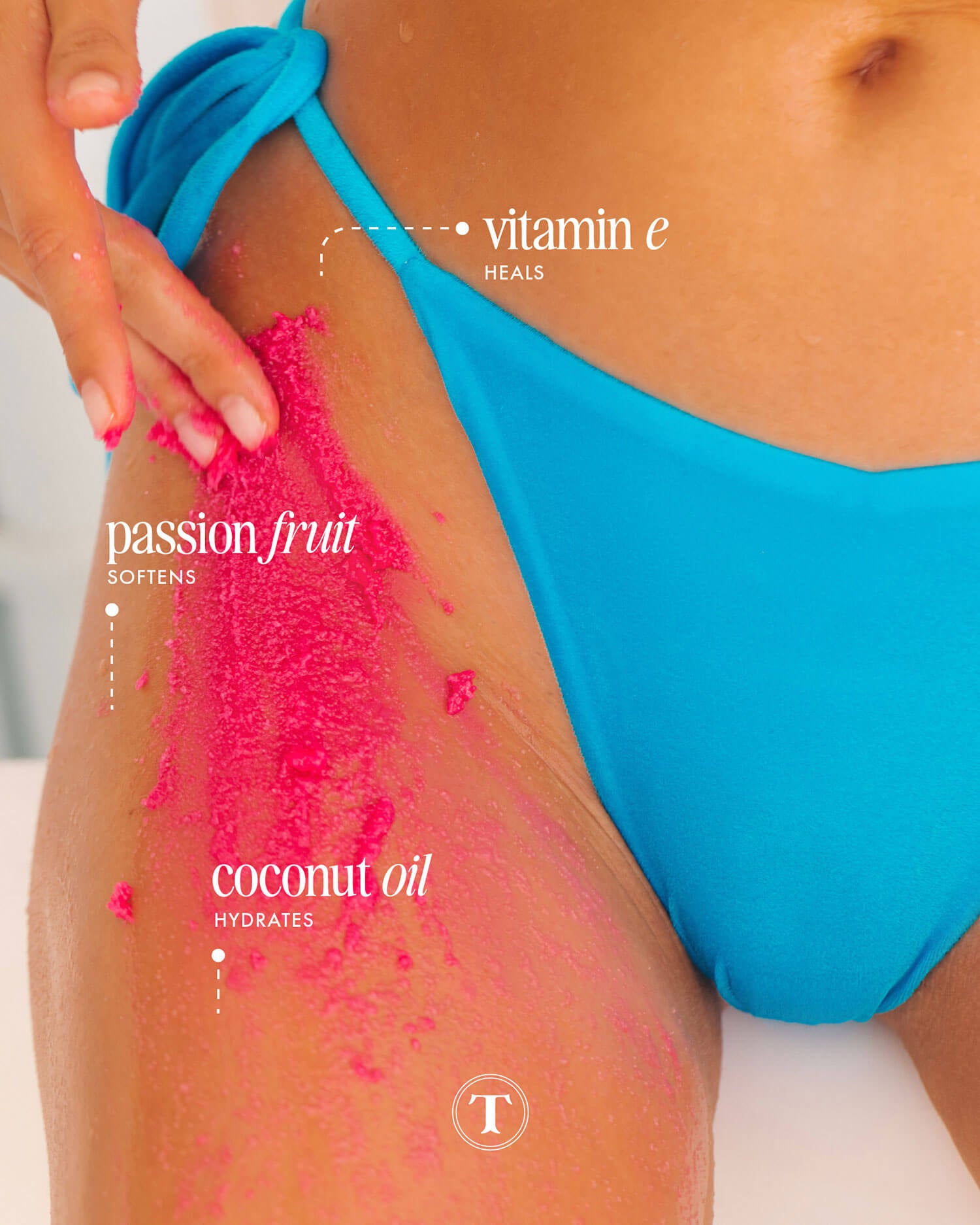 A woman in a blue bikini applies Truly Beauty’s Smooth Legend Pre-Shave Scrub, featuring vitamin E to heal, passion fruit to soften, and coconut oil to hydrate, for glowing skin on her thigh.