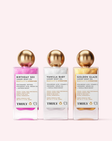 The Truly Beauty Luxury Body Oil Trio features three shimmer oils—Birthday Sex (pink), Vanilla Baby (white), and Golden Glaze (gold)—in gold-capped bottles, each enriched with bakuchiol and vitamin C.
