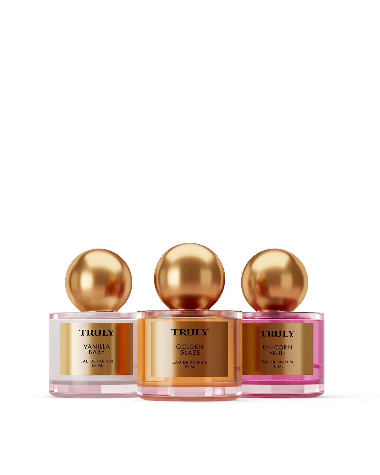 The Perfumers Set by Truly Beauty features three perfume bottles with gold spherical caps—Vanilla Baby, Golden Glaze, and Unicorn Fruit—lined up on a light pink background, offering an irresistible fragrance discovery.