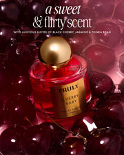 Cherry Baby Eau De Parfum by Truly Beauty sits among fresh dark cherries, described as a sweet and flirty black cherry scent with jasmine and tonka bean notes—ideal for anyone who loves a long-lasting fragrance.