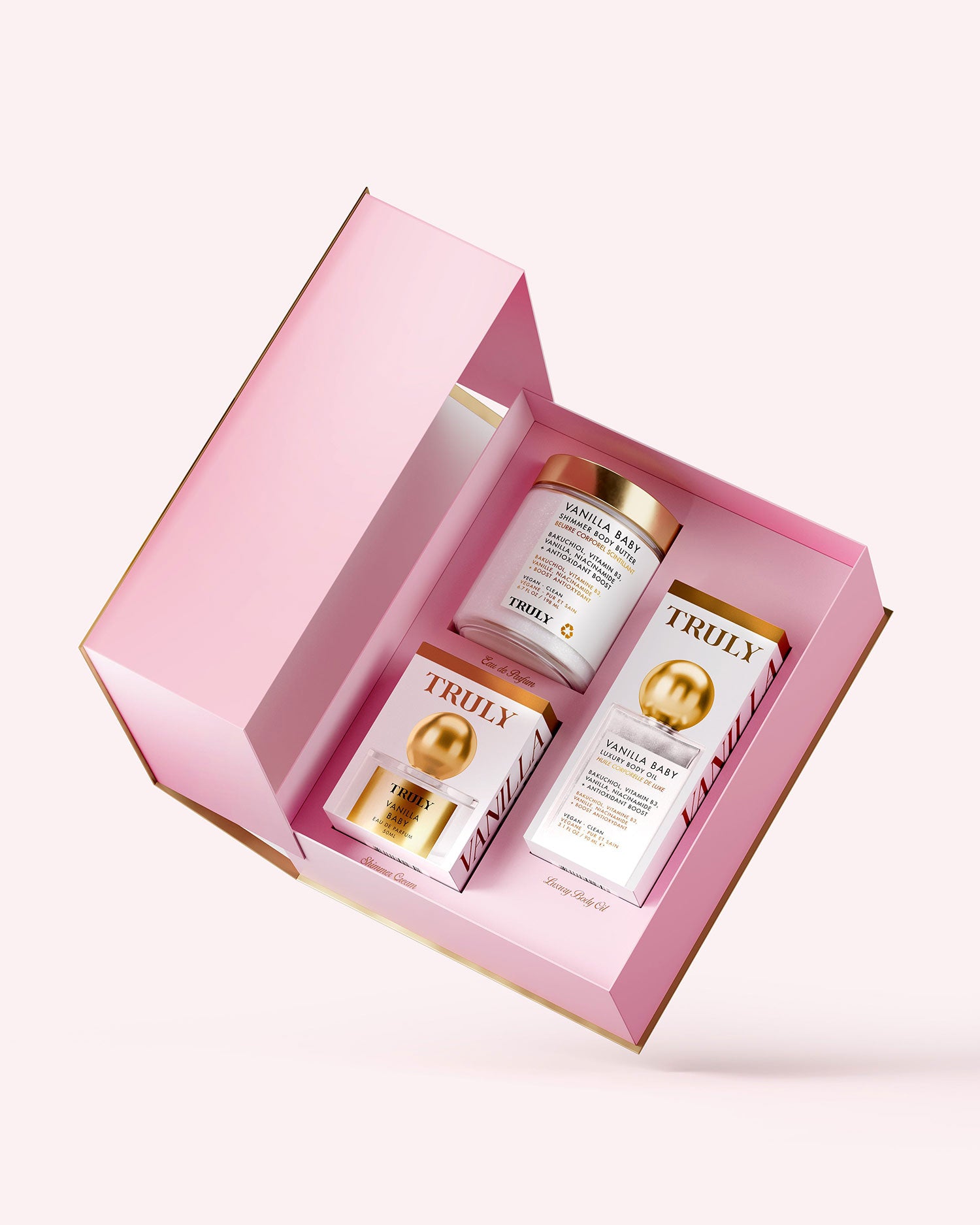 An open pink gift box featuring the Truly Beauty Vanilla Baby PR Box and two rectangular gold and white labeled boxes, all displayed on a light pink background.