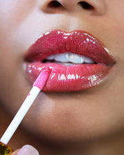 A close-up of lips as The Shimmer Duo by Truly Beauty is applied with a wand, delivering a smooth, shiny pink finish and a radiant glow.