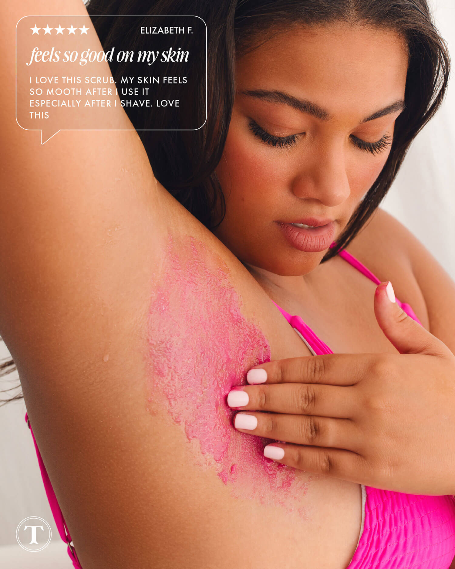 A woman in a pink top gently exfoliates her underarm with Truly Beauty’s Smooth Legend Pre-Shave Scrub, revealing glowing skin. In the corner, a testimonial says, “Feels so good—my skin feels so smooth after I use it.”.