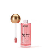 A bottle of Truly Beauty Luxury Peptide Lip Oil with a gold-topped applicator wand, filled with pink liquid, displayed against a light white background.