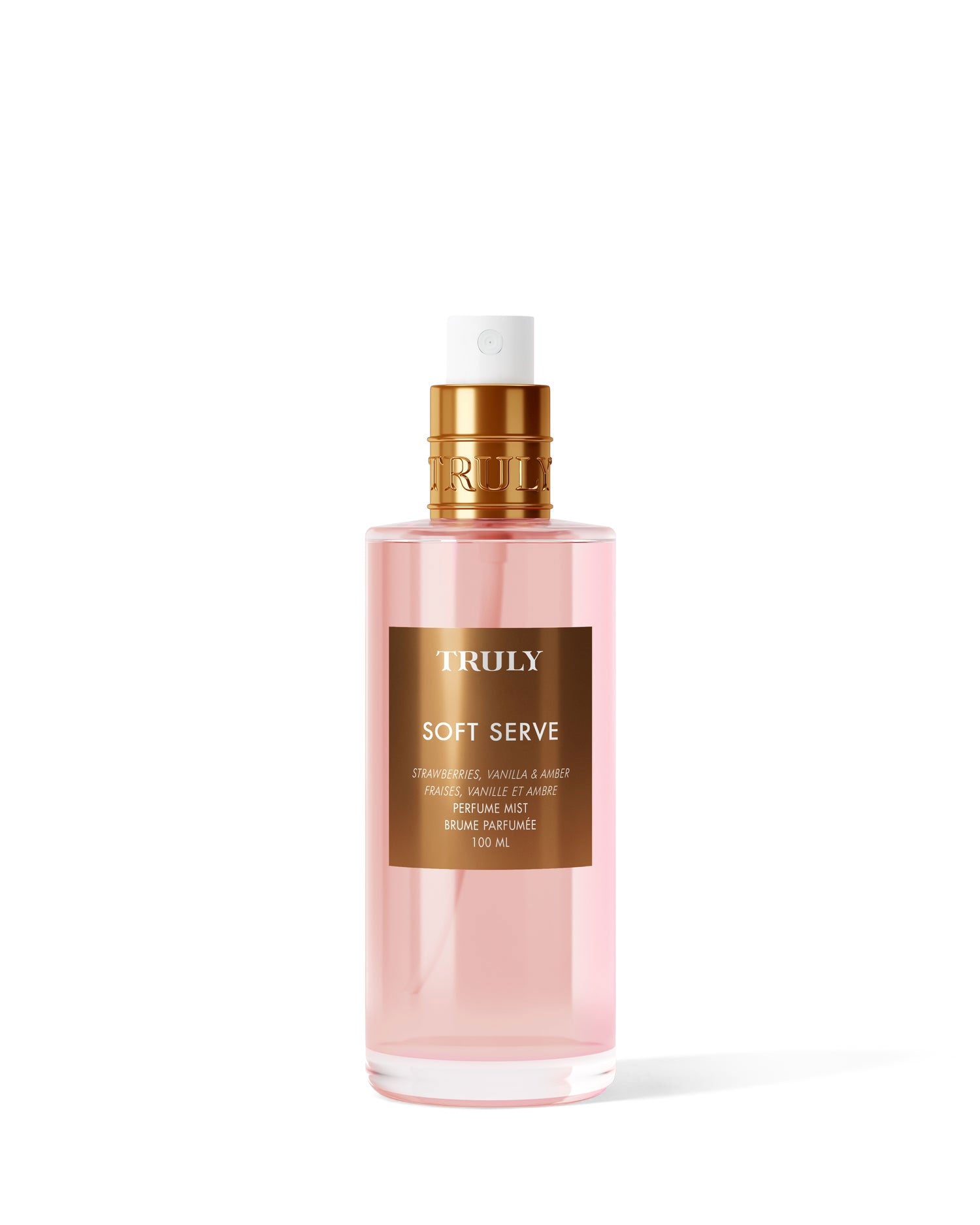 A clear pink bottle of Truly Beauty Soft Serve Perfume Mist features a gold spray top and label, showcasing its luxurious strawberries and cream scent with a hint of vanilla, set against a white background.
