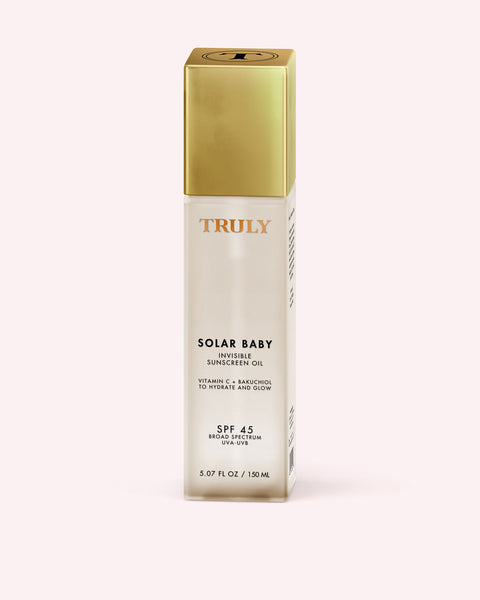 Skincare bottle labeled 'Truly Solar Baby' with gold cap on a white background