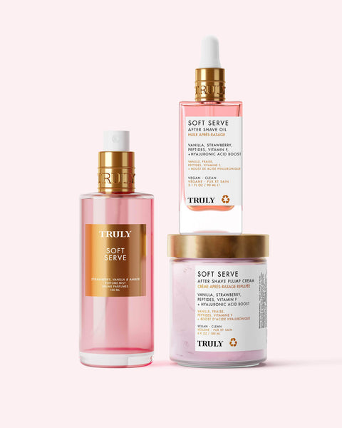 Three pink products from Truly Beauty’s Soft Serve Luxury Trio—spray bottle, dropper bottle, and “Soft Serve” jar—are displayed against a light background, offering strawberry-scented hydration with peptides and strawberry extract.