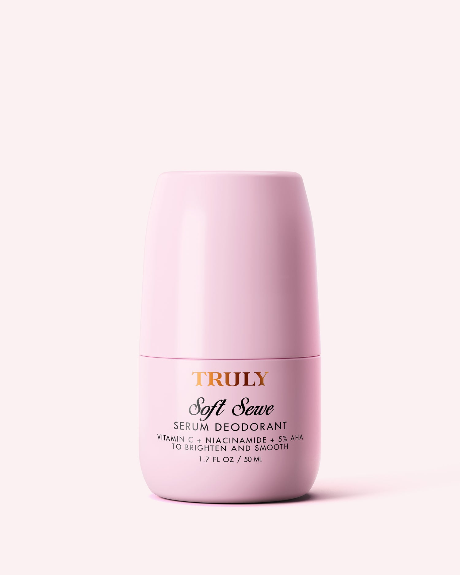 A pink cylindrical container of Truly Beauty Soft Serve Serum Deodorant with gold and black text sits against a light pink background. This vitamin C formula claims to brighten and smooth, featuring niacinamide and AHAs.