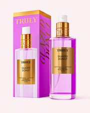 A pink and gold bottle of Truly Beauty Glazed Donut Perfume Mist stands beside its matching box, labeled “Toasted Vanilla + Buttercream Perfume Mist, 100 mL,” on a soft pink background.