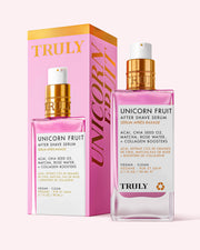 A bottle and box of Truly Beauty Unicorn Fruit After Shave Serum. The clear bottle with a gold and white pump features pink and gold text; the pink and yellow box displays UNICORN EDIT in large gold letters for soothing post-shave redness.