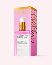 A pink bottle of Truly Beauty Unicorn Fruit After Shave Serum with a gold and white pump sits before its matching box. The vegan, clean formula soothes post-shave redness and combats ingrowns.