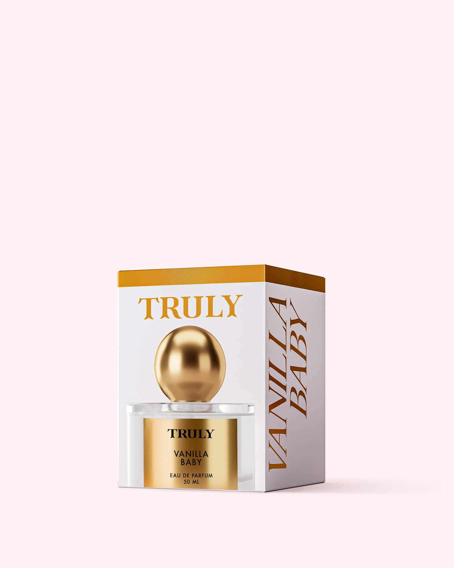 A gold and white bottle of Truly Beauty’s Vanilla Baby Eau De Parfum stands before its matching box with gold accents and bold branding, set against a light pink background that echoes the scent’s caramel drizzle and amber notes.