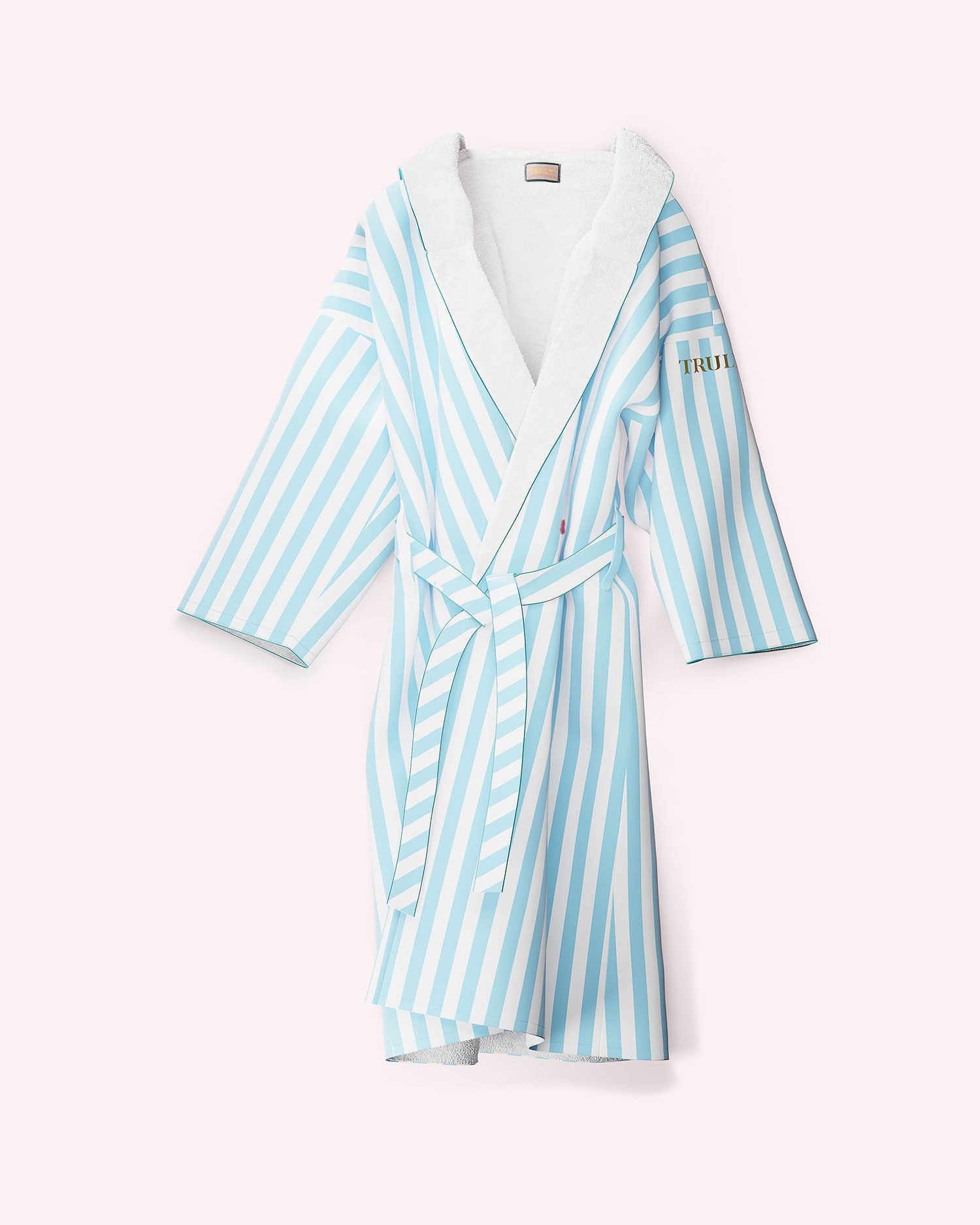 The Mykonos Luxury Robe by Truly Beauty features light blue and white vertical stripes, a matching belt, ultra-soft sherpa lining, and TRUTH embroidered in gold on the left sleeve, shown against a light pink background.