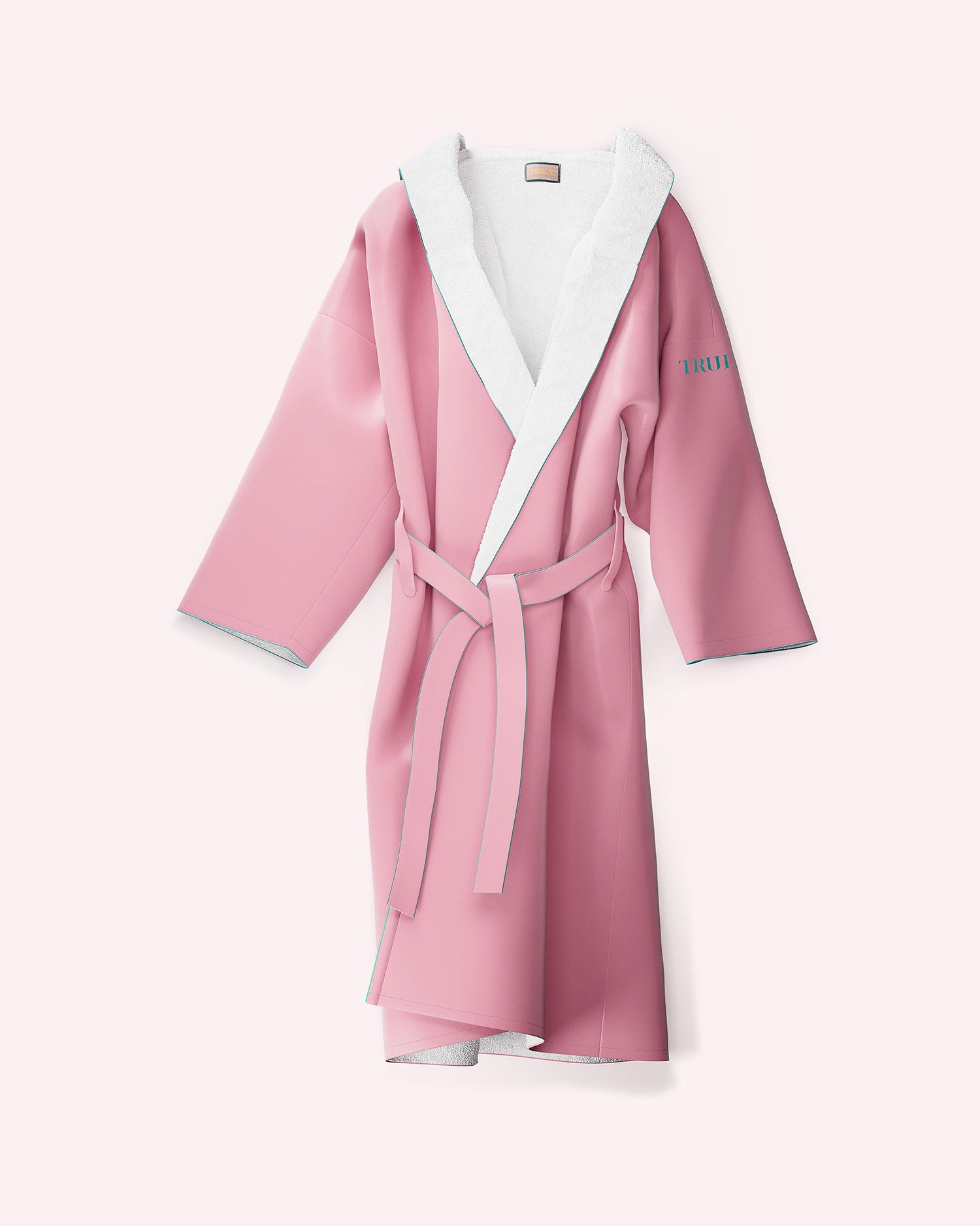 The Truly Beauty Signature Luxury Bathrobe is a pink, one-size-fits-all robe with a white collar and lining, soft polyester fabric, matching waist belt, and TRUTH in blue on the left sleeve. Displayed on a light pink background.