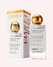 A bottle and box of Truly Beauty’s Vanilla Baby Luxury Body Oil with a gold spherical cap. The white and gold packaging highlights anti-aging ingredients like bakuchiol, vitamin B3, and niacinamide for plump, radiant skin.