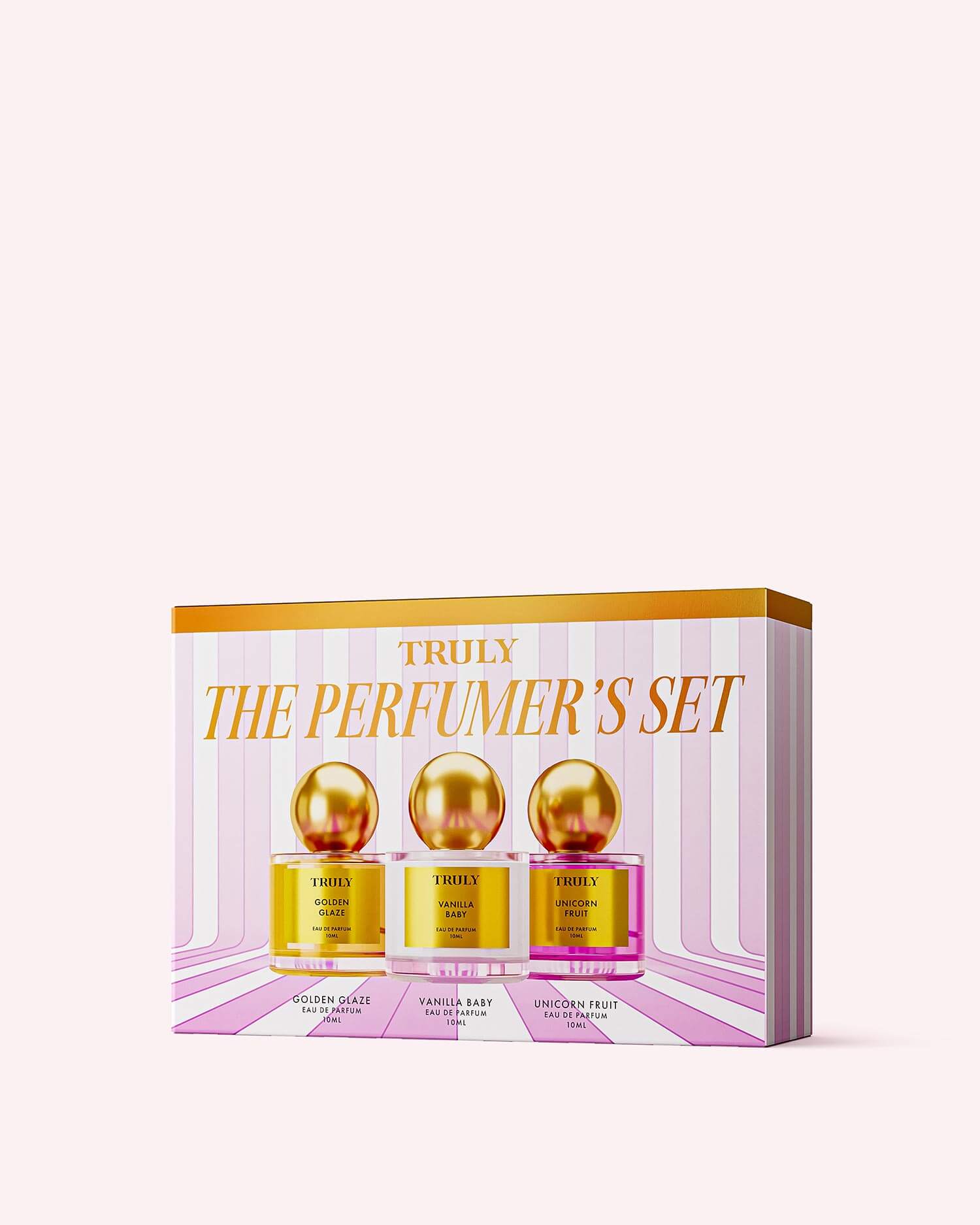 The Perfumers Set by Truly Beauty includes three gold-lidded jars—Golden Glaze, Vanilla Baby, and Unicorn Fruit—each with a unique scent, all displayed on a pink and white striped background.