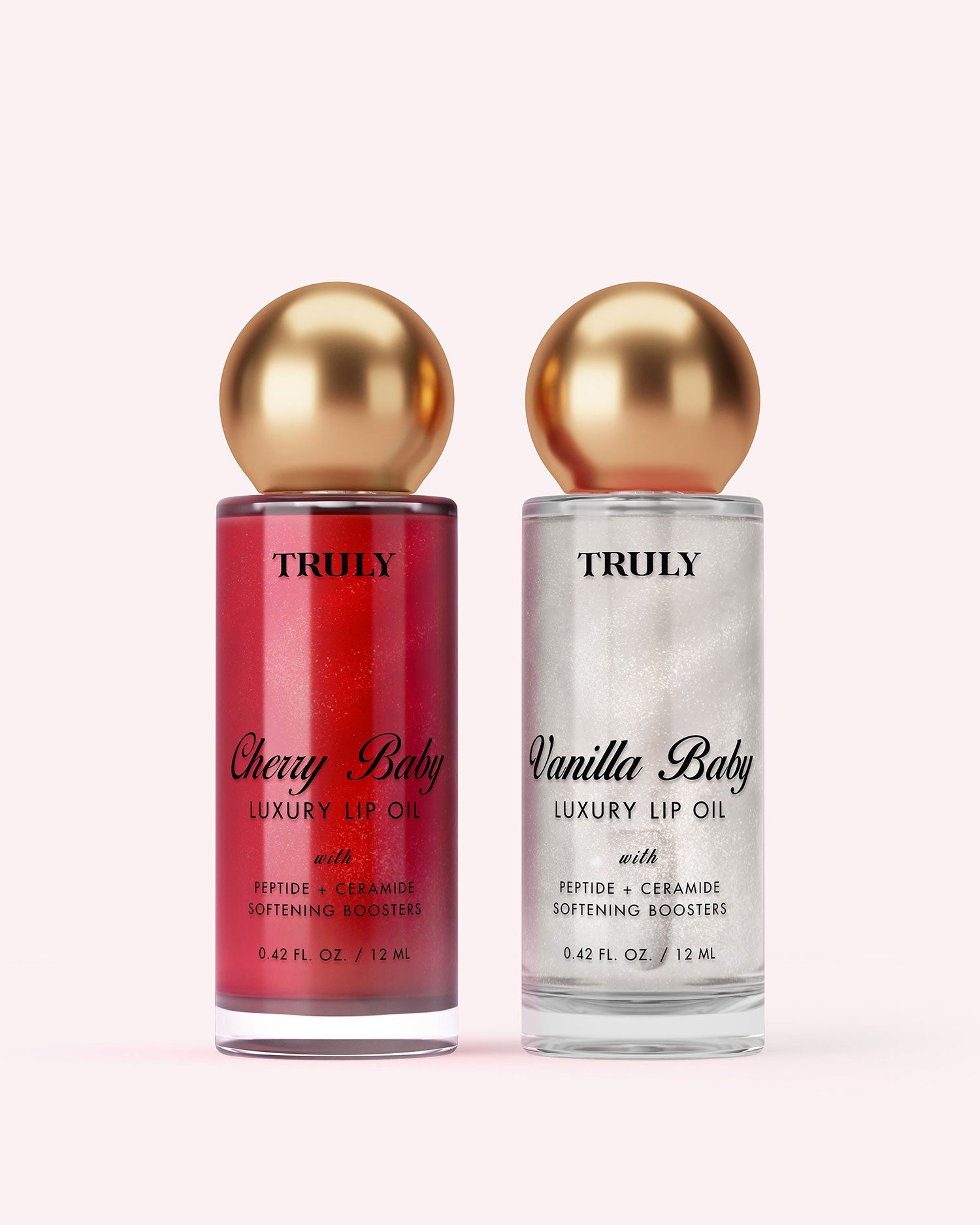 A bottle of Truly Beauty Luxury Peptide Lip Oil with pink liquid and a gold-capped applicator wand dipped in the oil, set against a light pink background.
