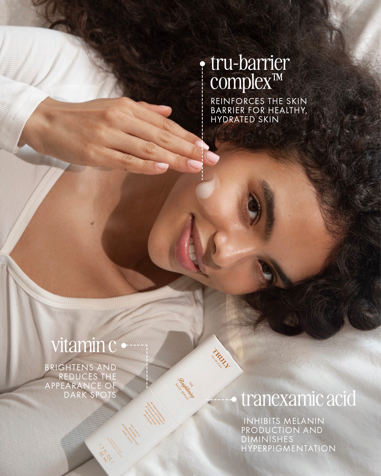 A curly-haired woman smiles while applying The Face Serum Duo by Truly Beauty. Text highlights its key ingredients—tru-barrier complex, vitamin C, and tranexamic acid—and clearly describes the benefits for radiant skin.