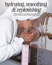 A person in a white bathrobe splashes water on their face by a sink with a gold faucet. On the counter is Truly Beauty’s The Face Serum Duo, known for its hydrating, smoothing, and replenishing effects.