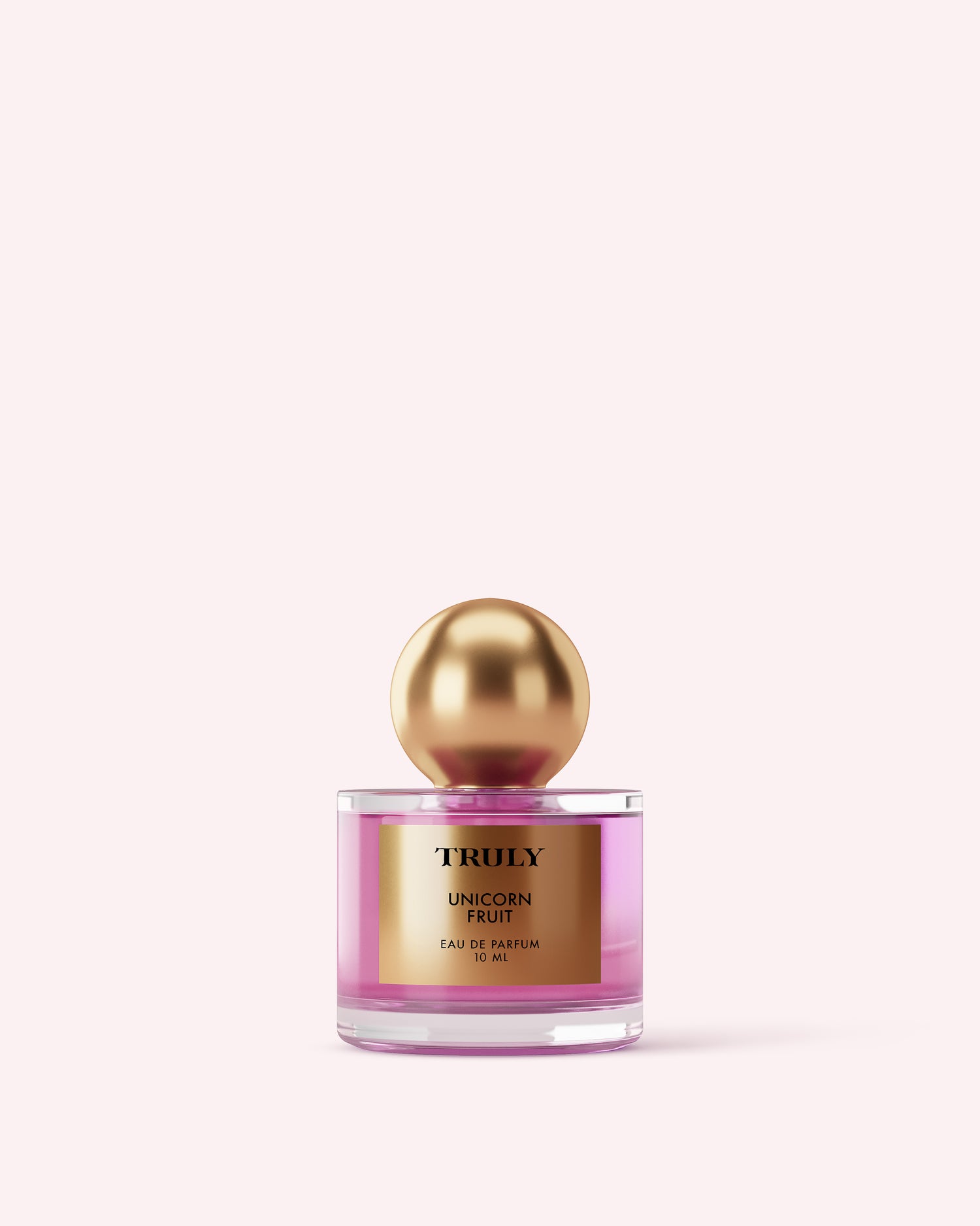 A bottle from Truly Beauty’s The Perfumers Set features pink liquid, a gold cap, and a gold label against a light pink backdrop—your next signature scent among Truly Beauty’s intoxicating fragrances.