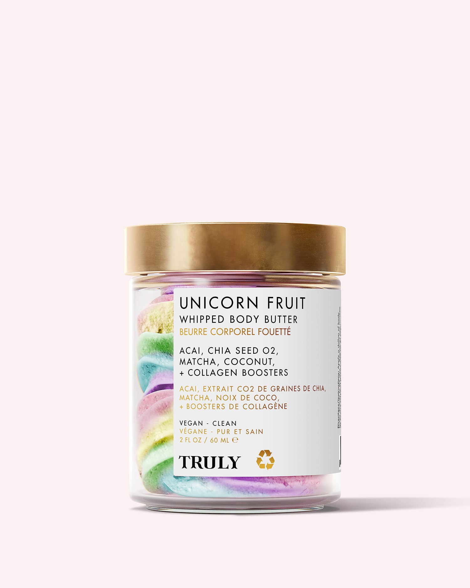 A clear jar with a gold lid holds Truly Beauty’s Unicorn Fruit Whipped Body Butter, featuring pastel swirls and natural ingredients like acai, chia seed oil, matcha, and coconut—ideal for dry skin.