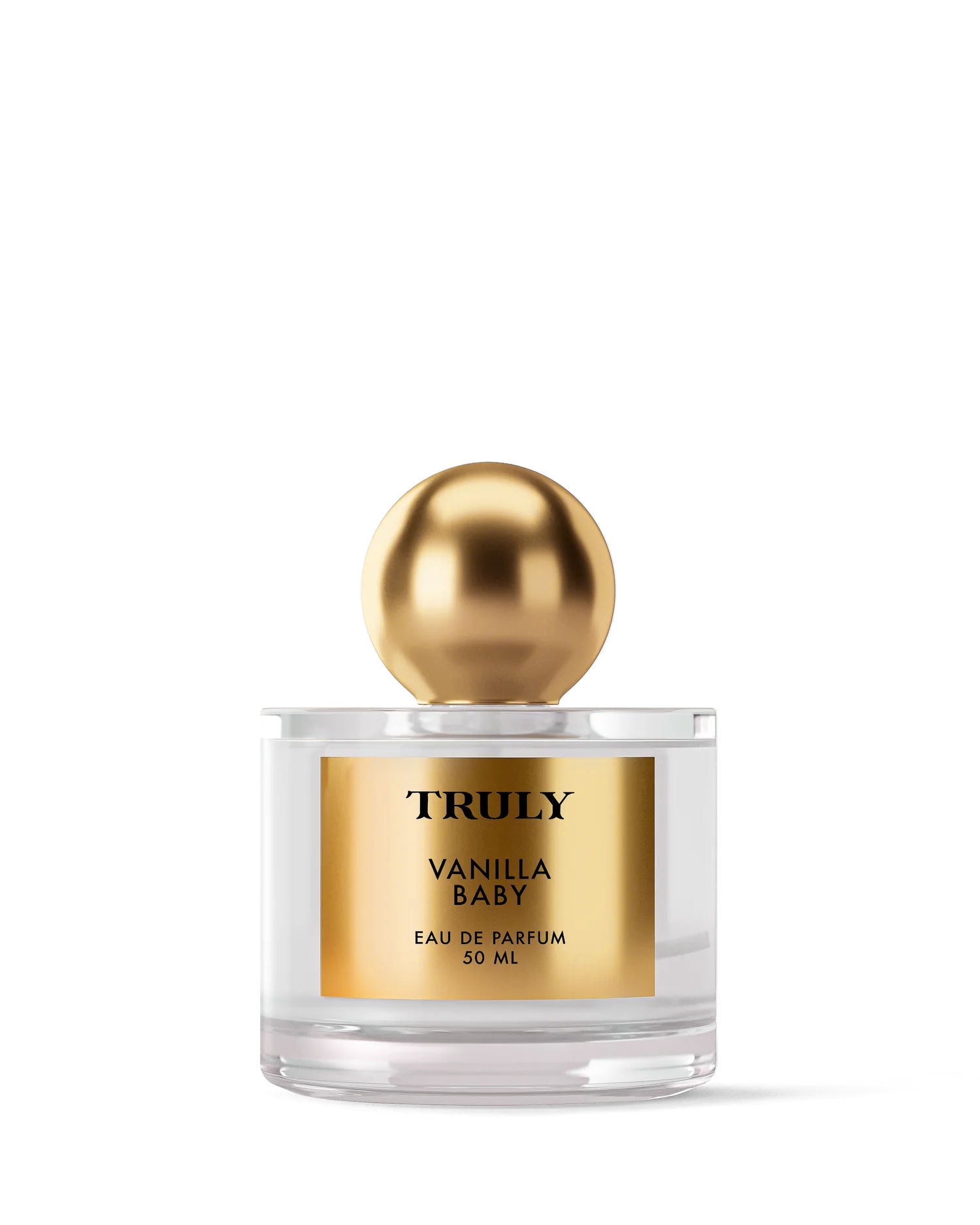 A clear glass bottle labeled Vanilla Baby Eau De Parfum by Truly Beauty features a shiny gold cap and label, set on a white background, suggesting sweet vanilla notes with hints of amber. 50 ml size.