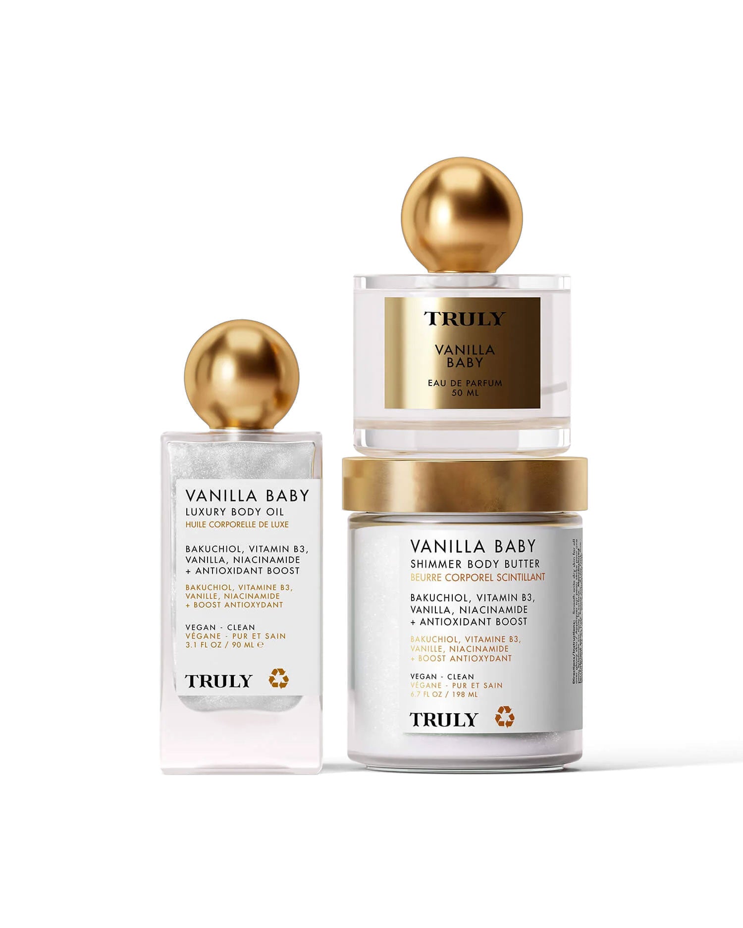 The Vanilla Baby Luxury Trio by Truly Beauty features body oil, shimmer body butter, and perfume—each with gold lids and white labels on a light pink background. Enjoy their warm vanilla scent for glowing, radiant skin all day.