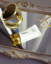 Gold and white 'Truly' perfume bottle on an ornate surface