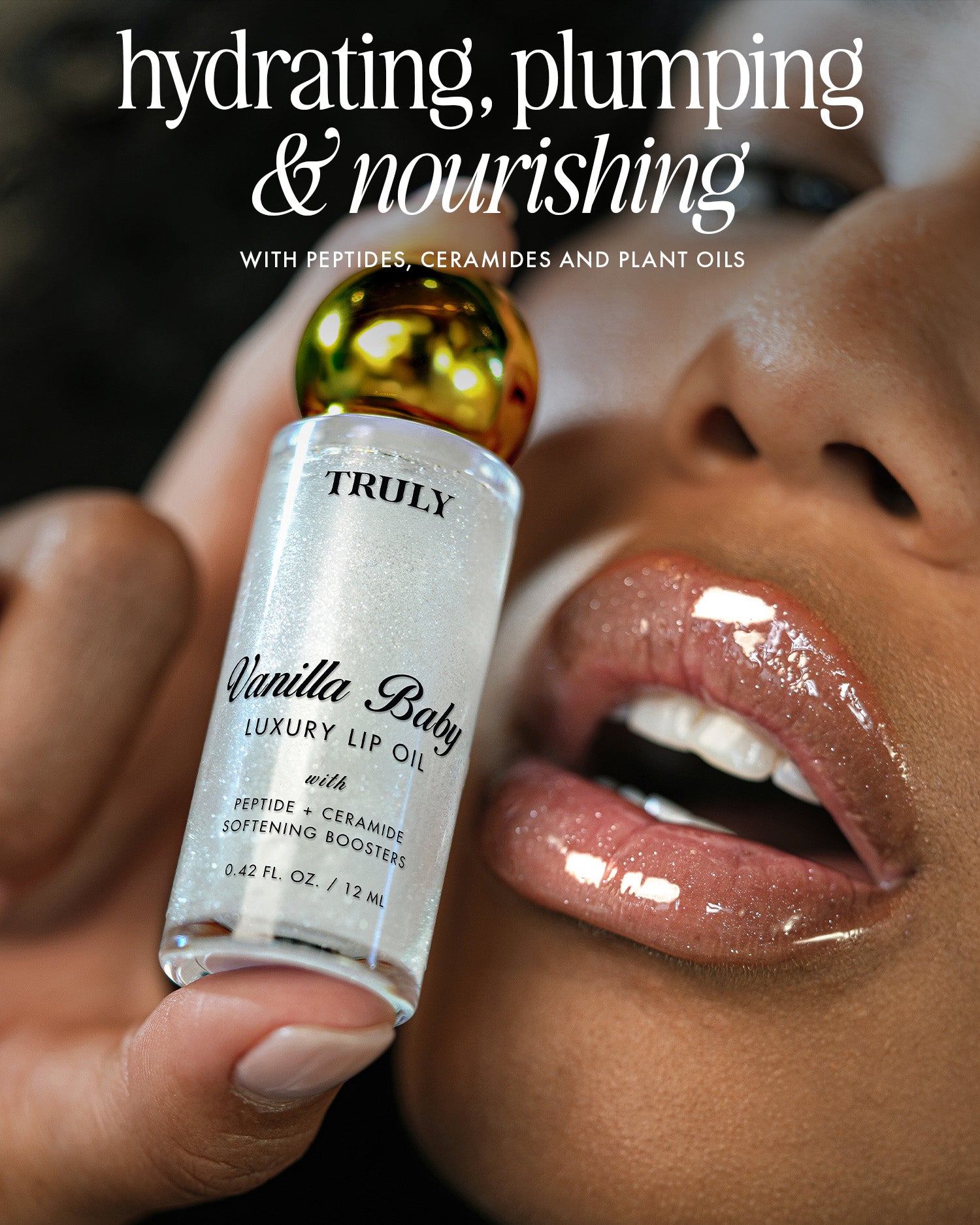 A close-up of a person applying The Shimmer Duo by Truly Beauty to their glossy lips. Text above reads: hydrating, plumping & nourishing with peptides, ceramides, and plant oils.