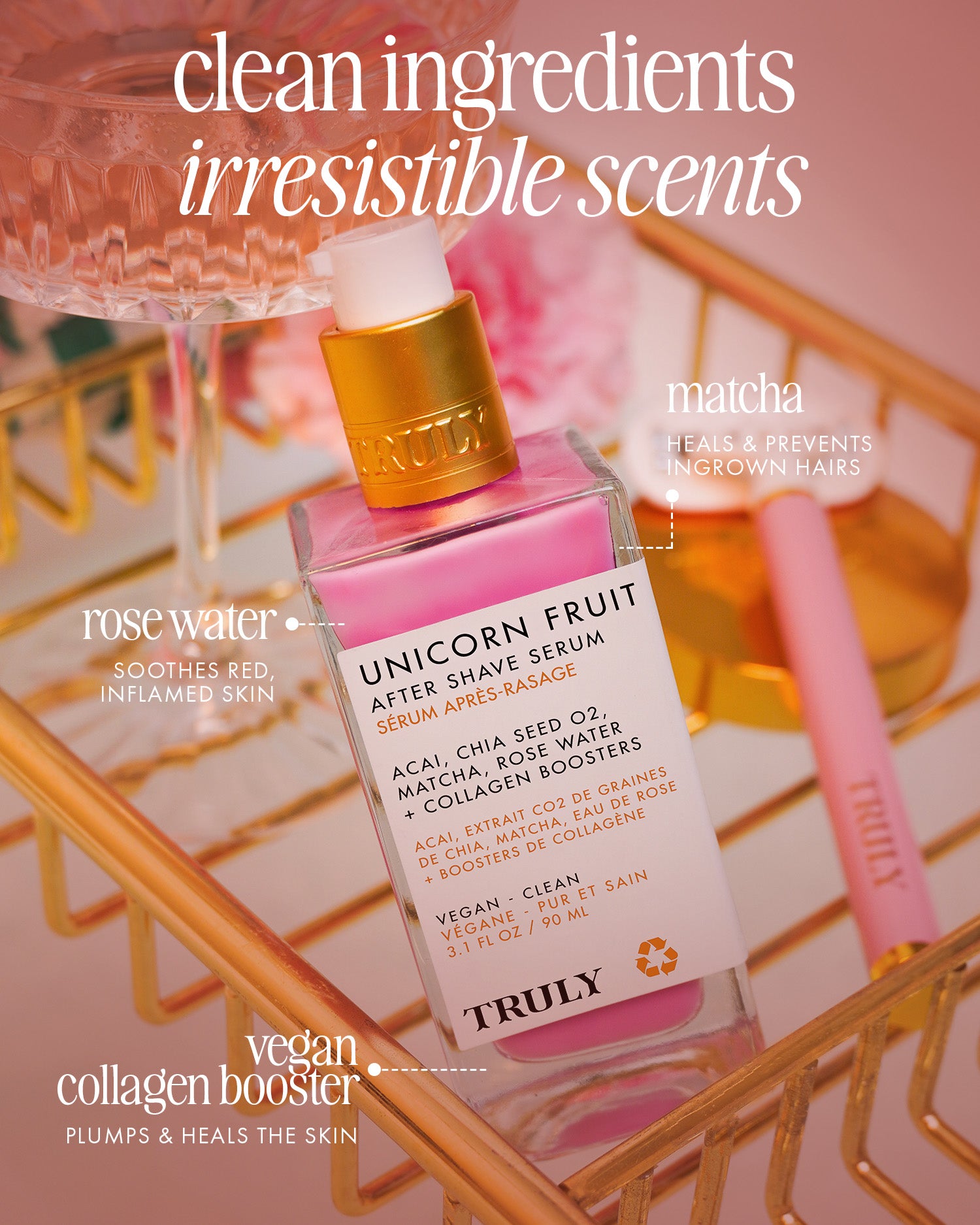 A pink bottle of Truly Beauty Unicorn Fruit After Shave Serum sits on a gold tray with a rose and beauty items, showcasing its clean ingredients, ingrown-fighting power, calming post-shave redness, plus rose water and vegan collagen benefits.